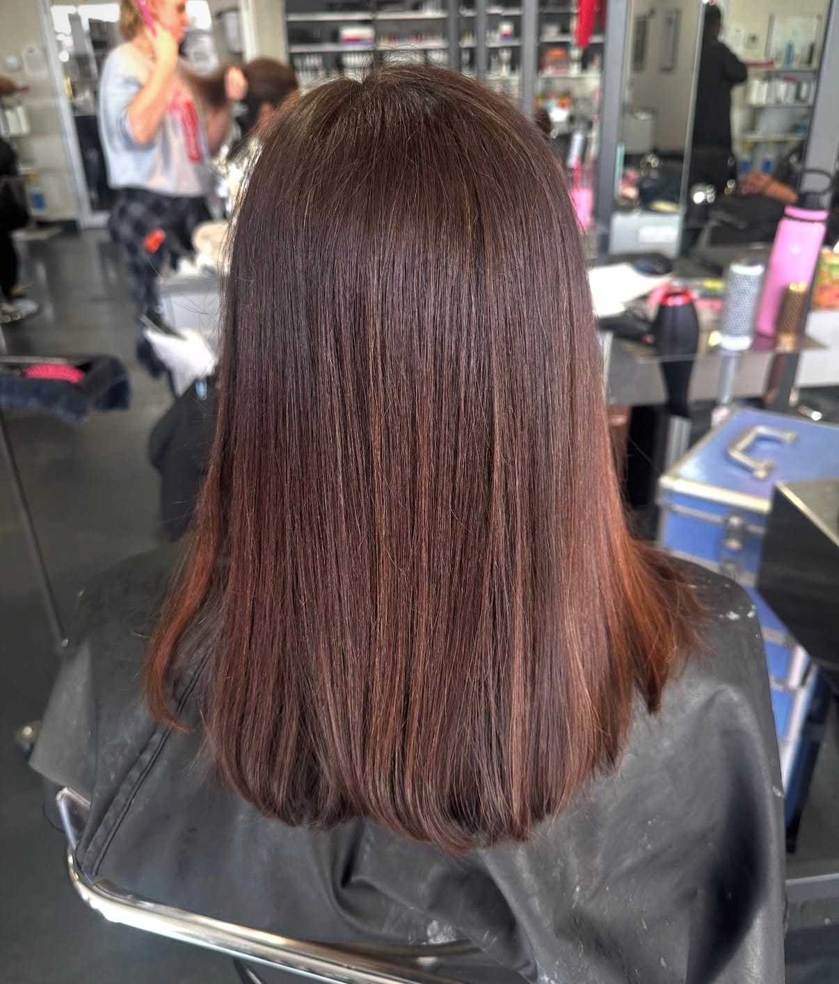 Hair salon scene with woman getting a fresh, straight shoulder-length haircut.