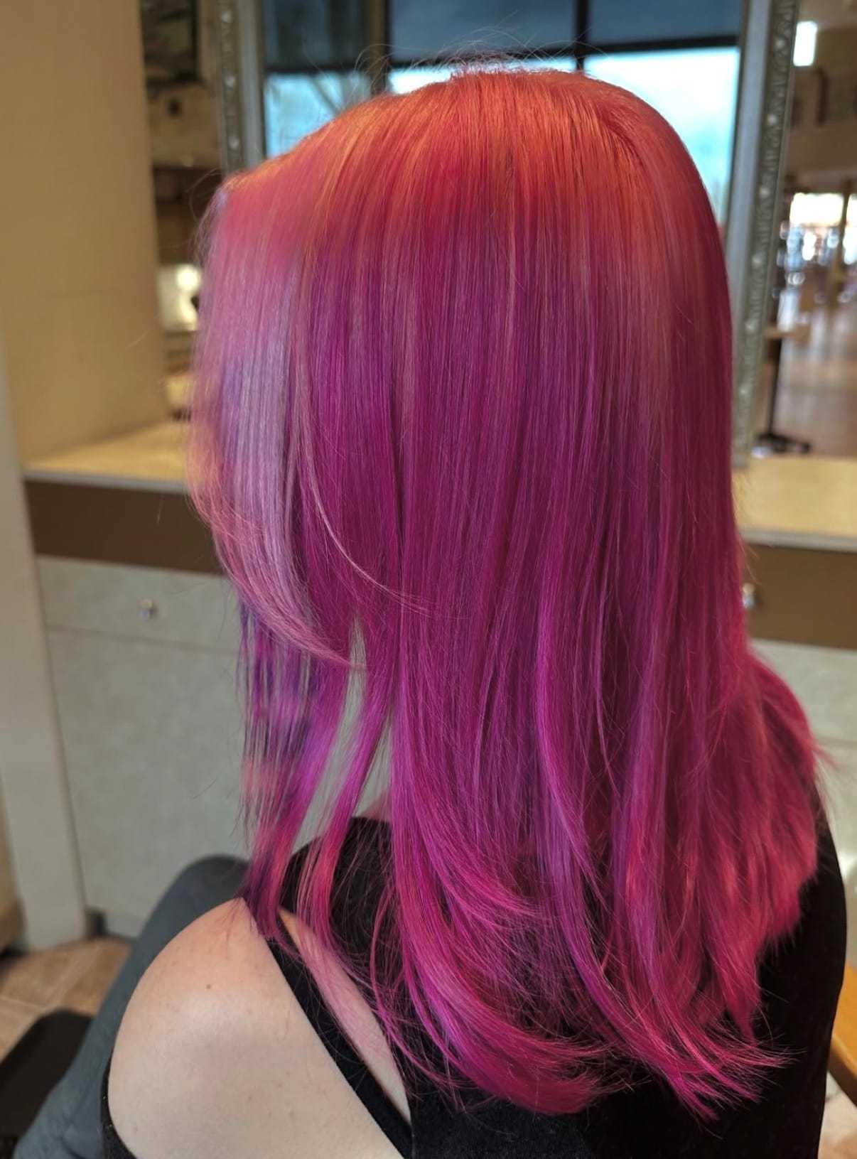 Vibrant pink and purple hairstyle in a salon setting.