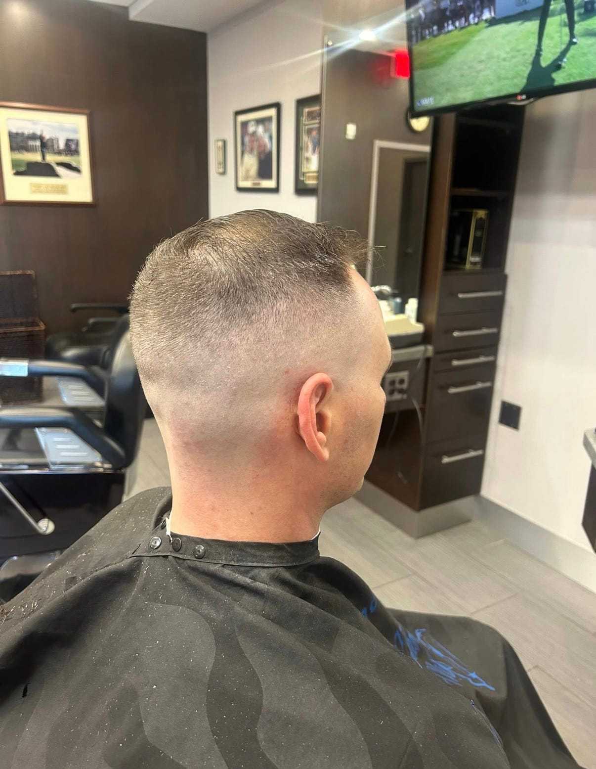 Man with a fresh fade haircut sits in a barbershop chair.
