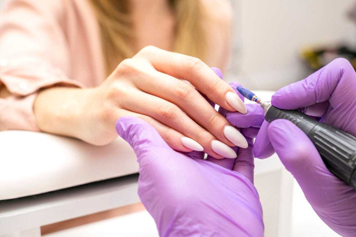 Nail technician applying polish on woman's nails.