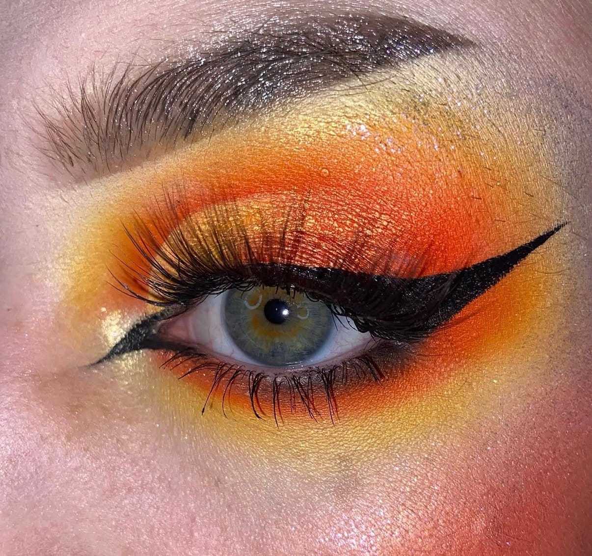 Bright eye makeup in shades of orange and yellow with bold black eyeliner.