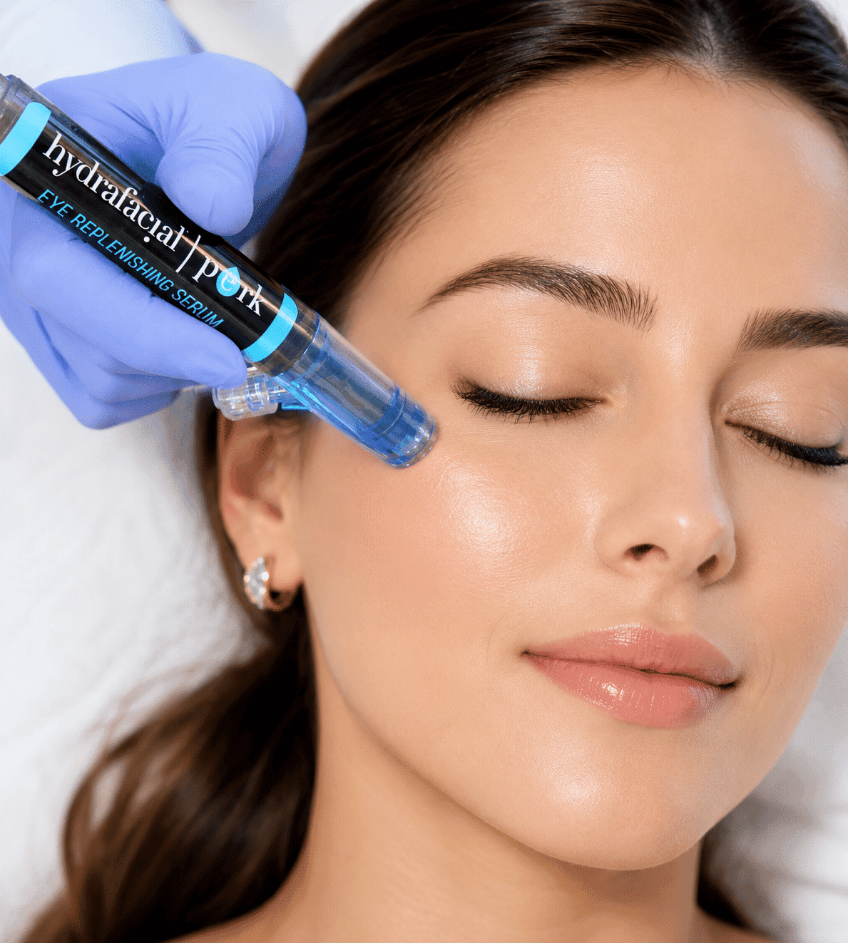A woman receiving eye rejuvenation treatment with a serum applicator.