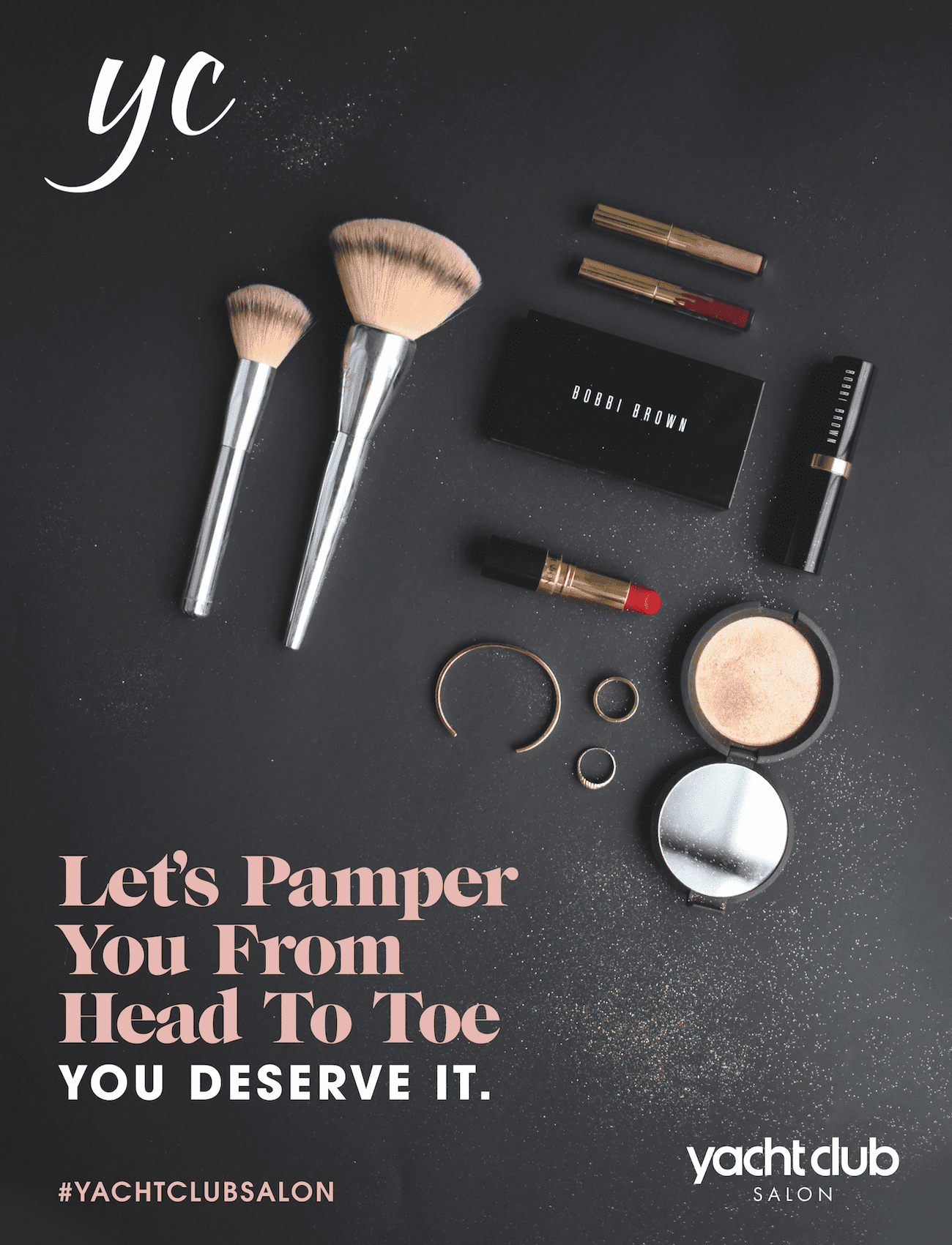 Beauty products and brushes arranged on a dark surface, featuring a salon's branding.
