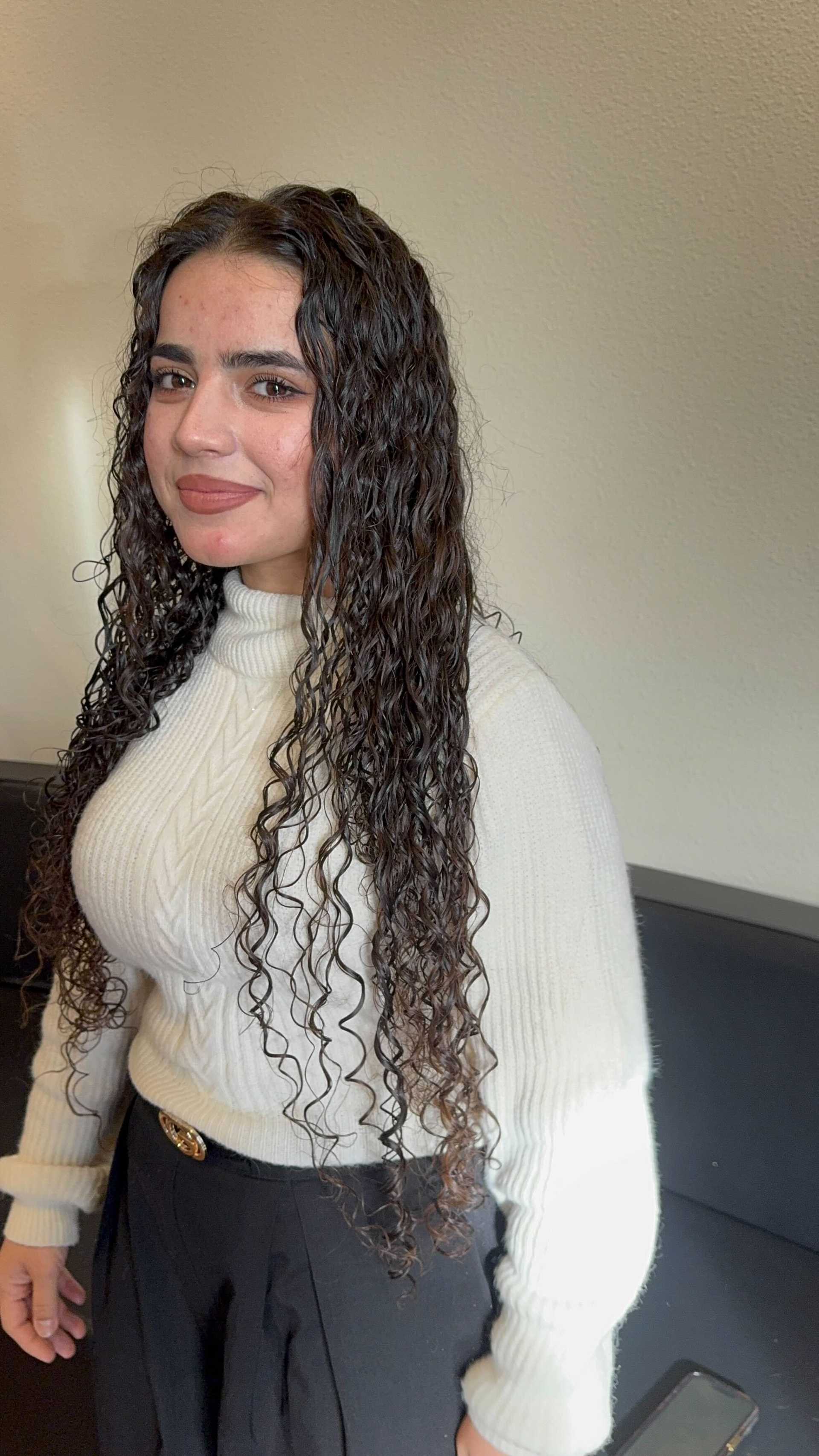 A person in a white sweater stands confidently against a light background.